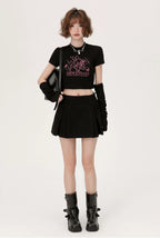 Person wearing a black outfit with a graphic design, standing against a white background.