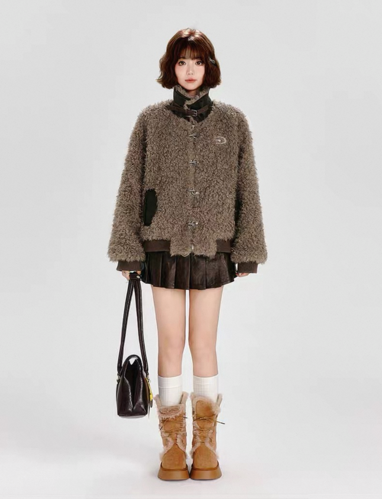 Person wearing a brown coat and boots with a handbag on a white background