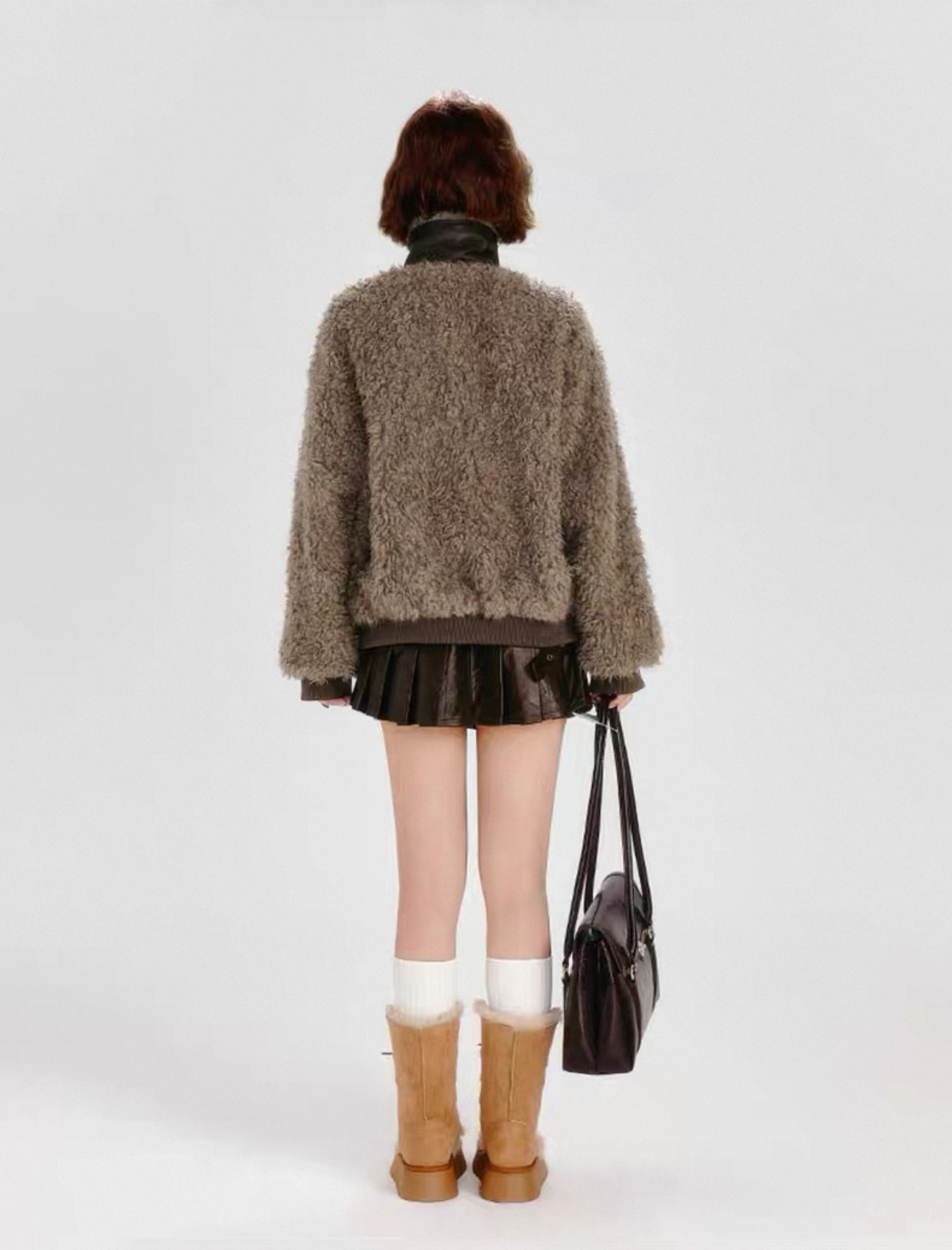 Person wearing a brown sweater and skirt with knee-high boots on a white background