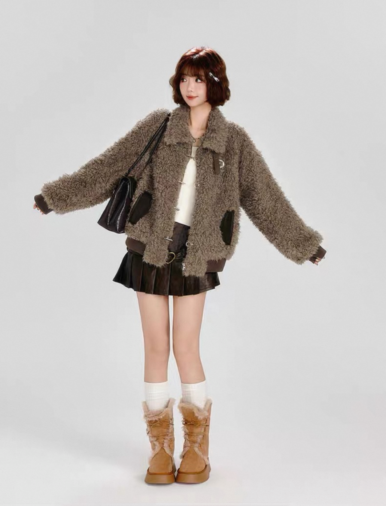 Person wearing a brown textured coat, black skirt, and brown boots on a gray background